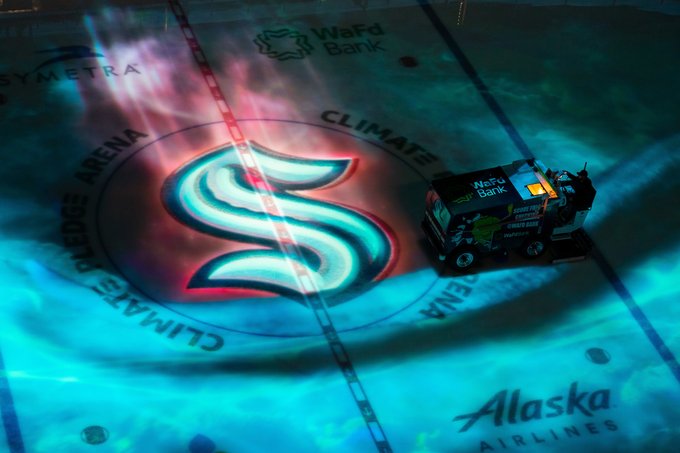 Photo of the center ice logo at Climate Pledge Arena illuminated with on-ice projection mapping