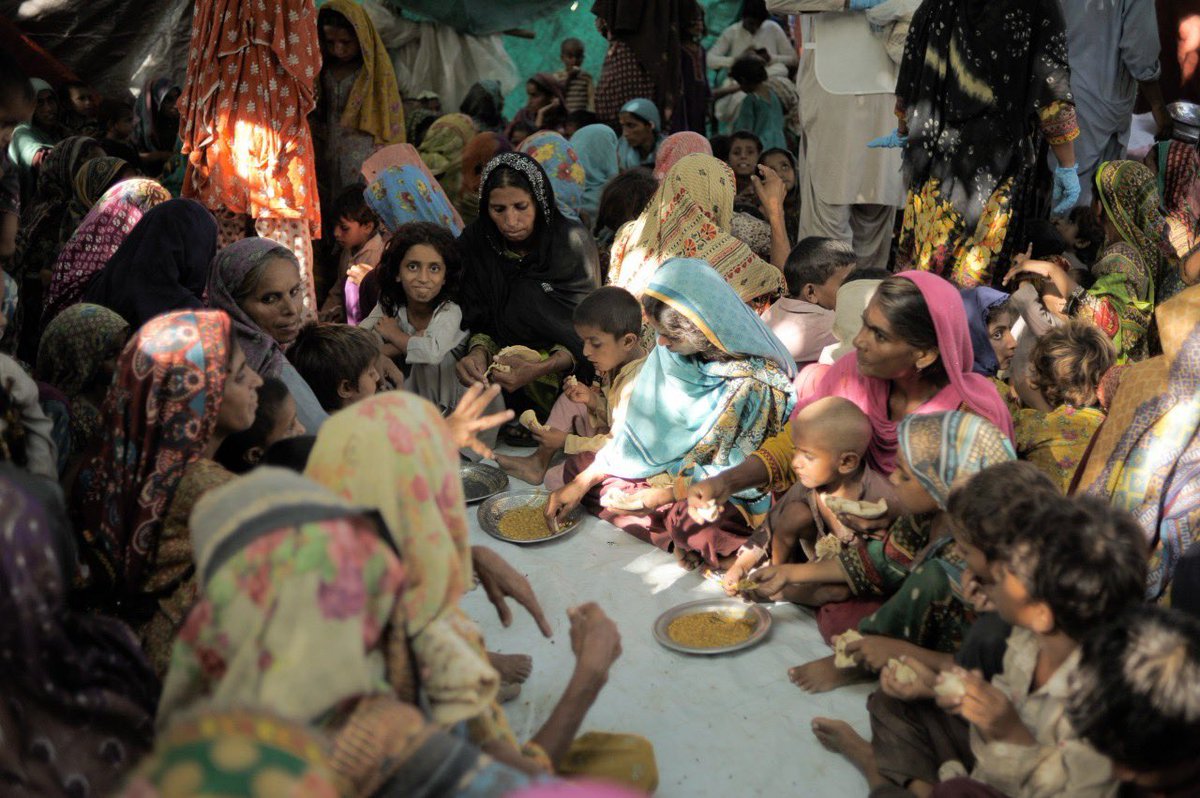 WCKitchen's tweet photo. The worst flooding in Pakistan’s history has left homes in the village of Ali Sher Kashmir inundated. Gathering in a drier area, women &amp; children sat under a mango tree to enjoy a WCK lunch. We’ll keep cooking &amp; are expanding to support more families in need. #ChefsForPakistan https://t.co/koS42j9v8T