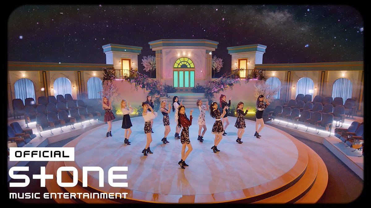 A K-pop girl group performs on a grand, ornate stage under a starry sky, with the text 'OFFICIAL STONE MUSIC ENTERTAINMENT' in the corner.