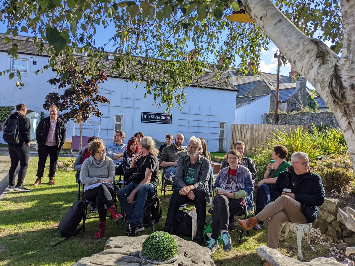 Byddi's tweet photo. The audience gathering early for the Speculative Flash Fiction in the garden. @Thesecretbooks1 had to borrow chairs from the cafe next door to accommodate everyone in listening to a stunningly talented bunch of writers. #Irishscifi #SpeculativeFiction #flashfiction @ACNIWriting https://t.co/NVaLcFWHjC