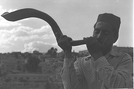 صورة تعود إلى عام 1959 لرجل يهودي يمني ينفخ في البوق (الشوفار) على جبل صهيون في أورشليم في رأس...