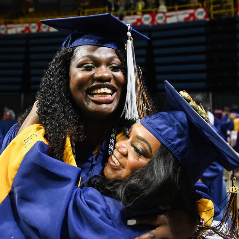 UTChattanooga's tweet photo. Ajasia Harris (right in the photo) hugs Ruona Uwusiaba during the UTC commencement ceremony in May. Harris is the first student from the Howard School to graduate from UTC with a degree in electrical engineering.