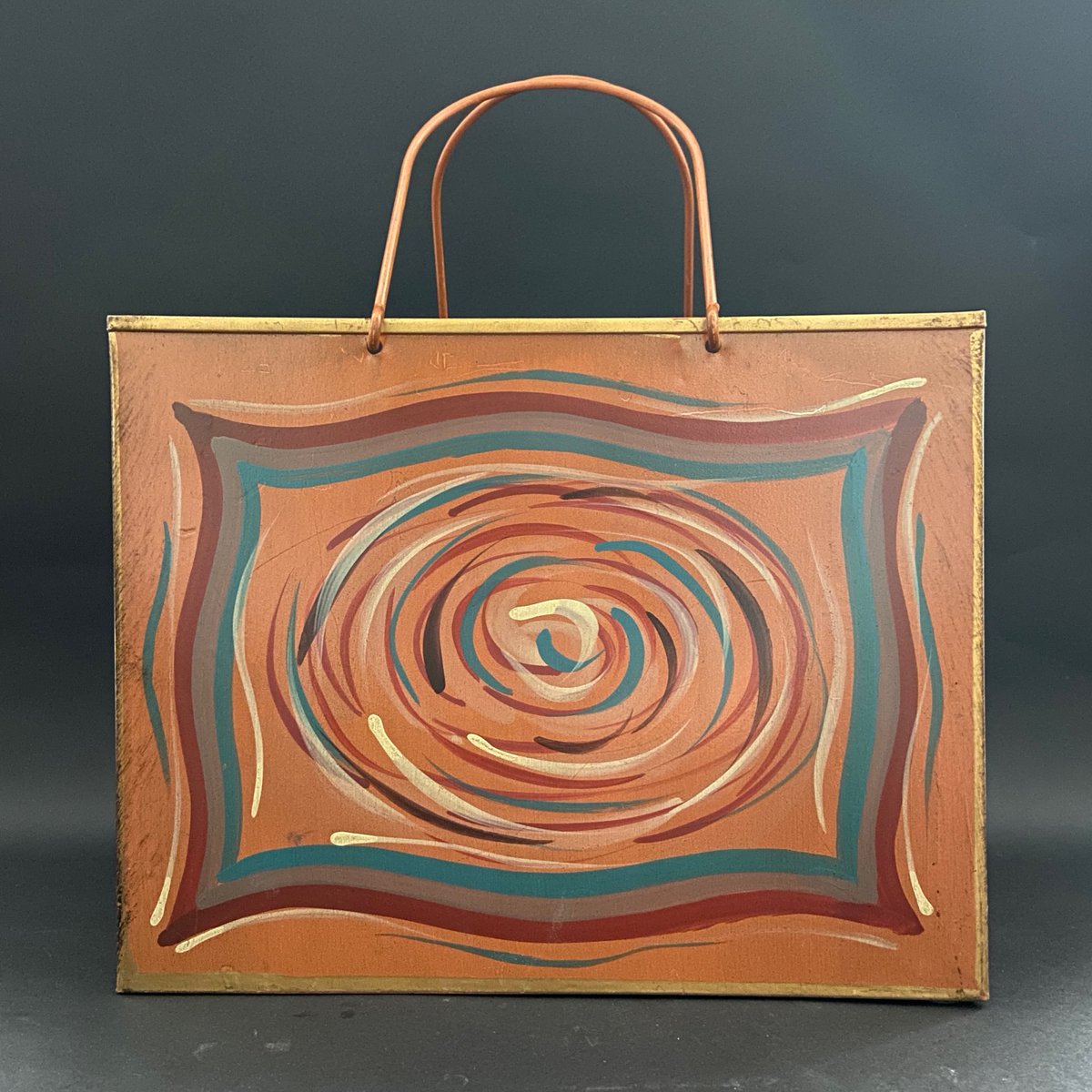 285/365: This orange-brown bag features a painted design in earth-colors that repeats on both sides. The bag is formed of metal panels with copper handles. 