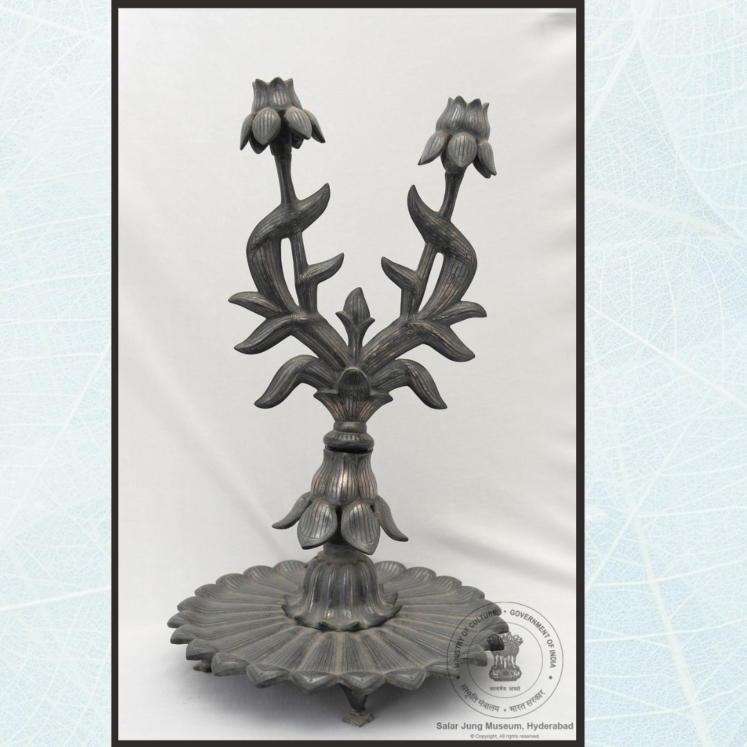 sjmhyd's tweet image. This Candelabra or Shamdan has detachable branches each having a flower shaped mouth. The stem is fitted to a lotus shaped tray. Linear designs are inlaid all over the leaves in silver, Bidar, 19th century.
#SalarJungMuseum #Candlestand #bidriware #candelabra