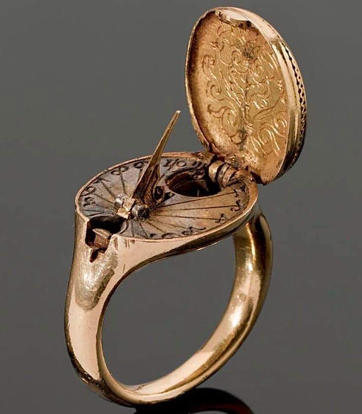 Gold Sundial and Compass ring, 1570 CE, possibly Germany. The hinged oval bezel designed as a seal and engraved with a coat of arms, opening to reveal a sundial and compass, on a plain gold hoop.

#archaeohistories