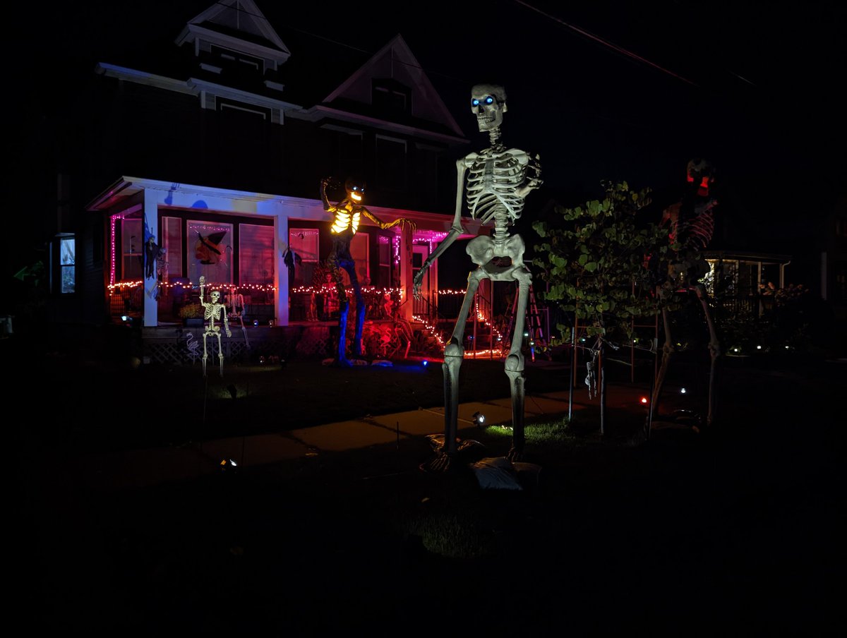MephistoMori's tweet photo. About halfway done decorating. Still gotta get on top of my porch. Set my gravestones and cemetery fence, sling some cobwebs and more lighting around, pose more skellingtons, set up the 15 footer (who's waiting on clothes) and naturally put an 8' spider on my roof. #SpookySZN https://t.co/5GKB4yOmUy