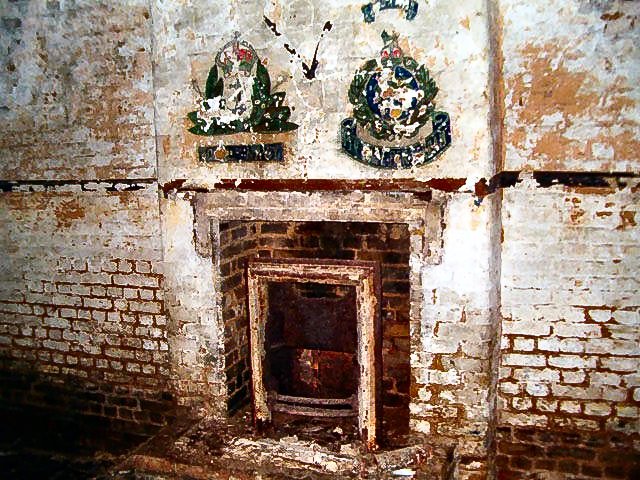 coalhouseforths's tweet photo. The opposite wall to the previous image of the Mess at Coalhouse Fort, but what are badges painted above the fire? https://t.co/u8LEsncMWO