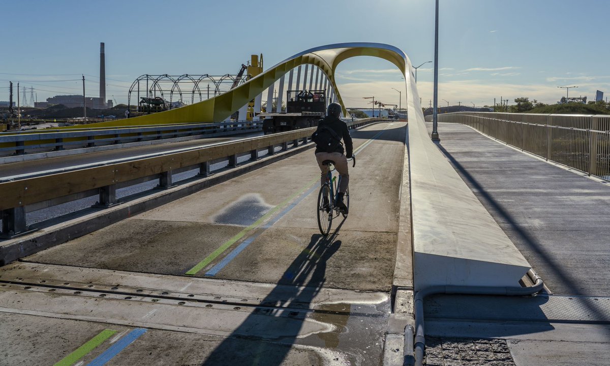 A cyclist riding in a separated, bi-directional bike lane, across a bridge.