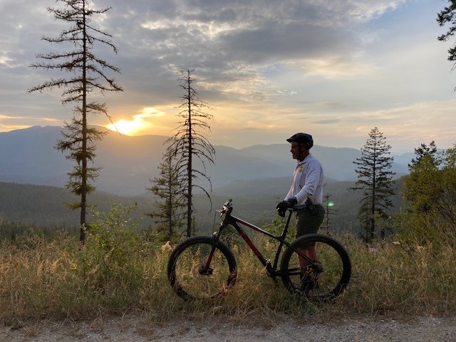 USBPChiefSPW's tweet photo. A Spokane Sector Bike Patrol Agent takes a pause under a Pacific Northwest sunset while patrolling the northern border. #BorderPatrol Agents often find themselves working in remote areas of international border inaccessible to motor vehicles. #HonorFirst #MetalineFalls https://t.co/SnlWbp4Ozv