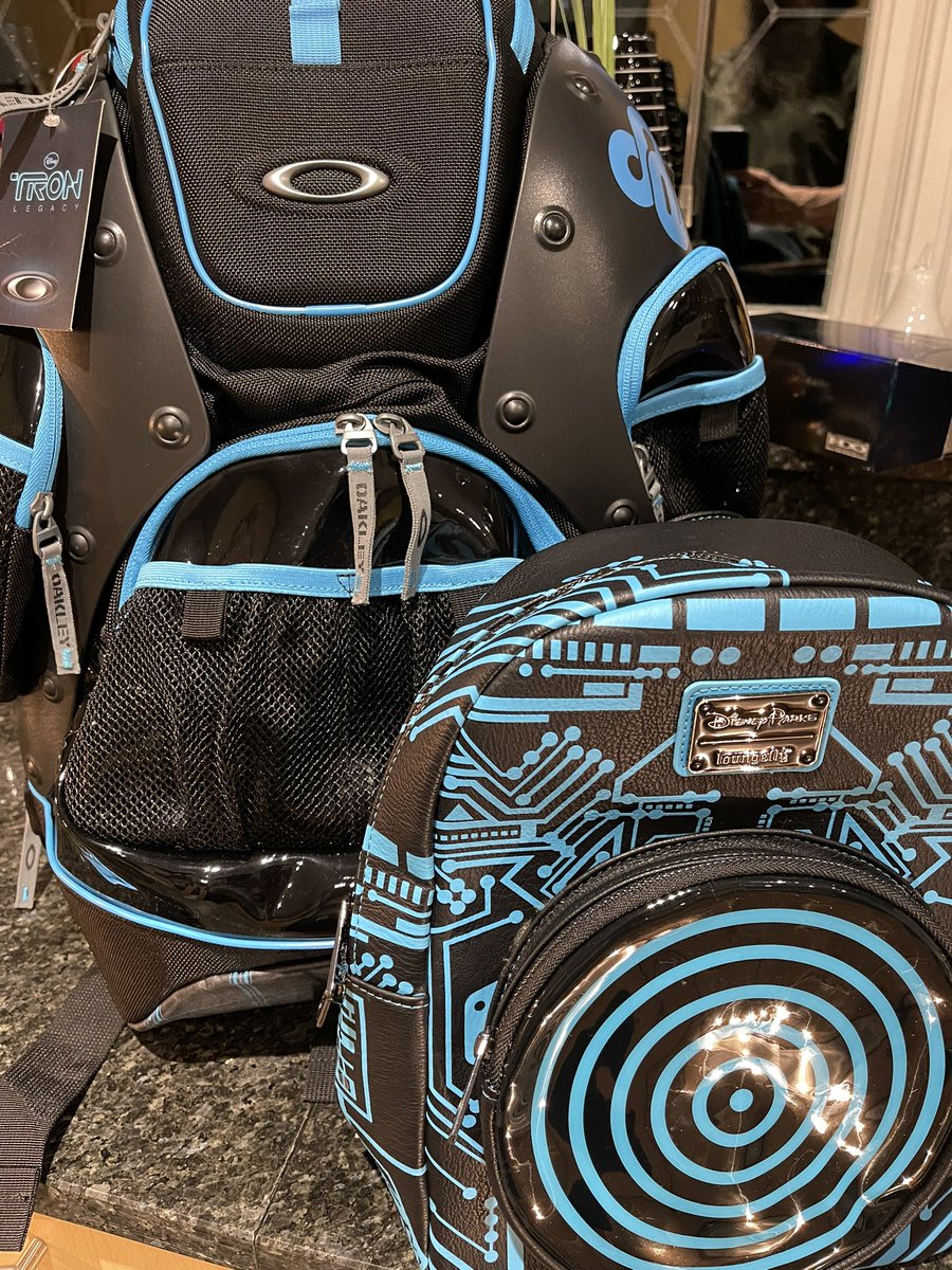 ch4os_theory's tweet photo. Loungefly Tron 40th anniversary mini backpack pictured with the Oakley Tron Legacy backpack from 2010. The ‘data disc’ on the back lights up #tron #tronlegacy #loungefly #myfirstloungefly #Disney #tron40 #oakley https://t.co/vtkevq8L0o