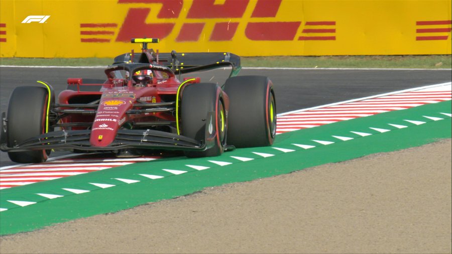 Ferrari's Carlos Sainz runs slightly wide through Degner, a fast right-handed corner. His Ferrari is partly on the track, but mostly positioned on top of the kerbs.