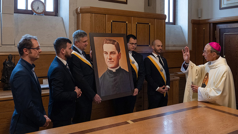 KofC's tweet photo. The supreme chaplain blesses a portrait of Blessed Michael McGivney in the sacristy of the St. John Paul II Shrine. The image is held by members of Blessed Michał Sopoćko Council 17667 in Kraków-Łagiewniki. (Photo by Tamino Petelinšek) https://t.co/4xcI8LT0qb