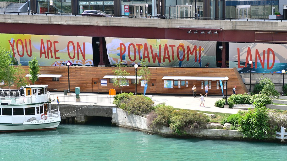 Picture of 'You Are on Potawatomi Land,' by artist Andrea Carlson (Ojibwe). Large painted banners declaring "You Are on Potawatomi Land" hang along the Chicago Riverwalk on Wacker Drive just east of the Michigan Ave Bridge.
