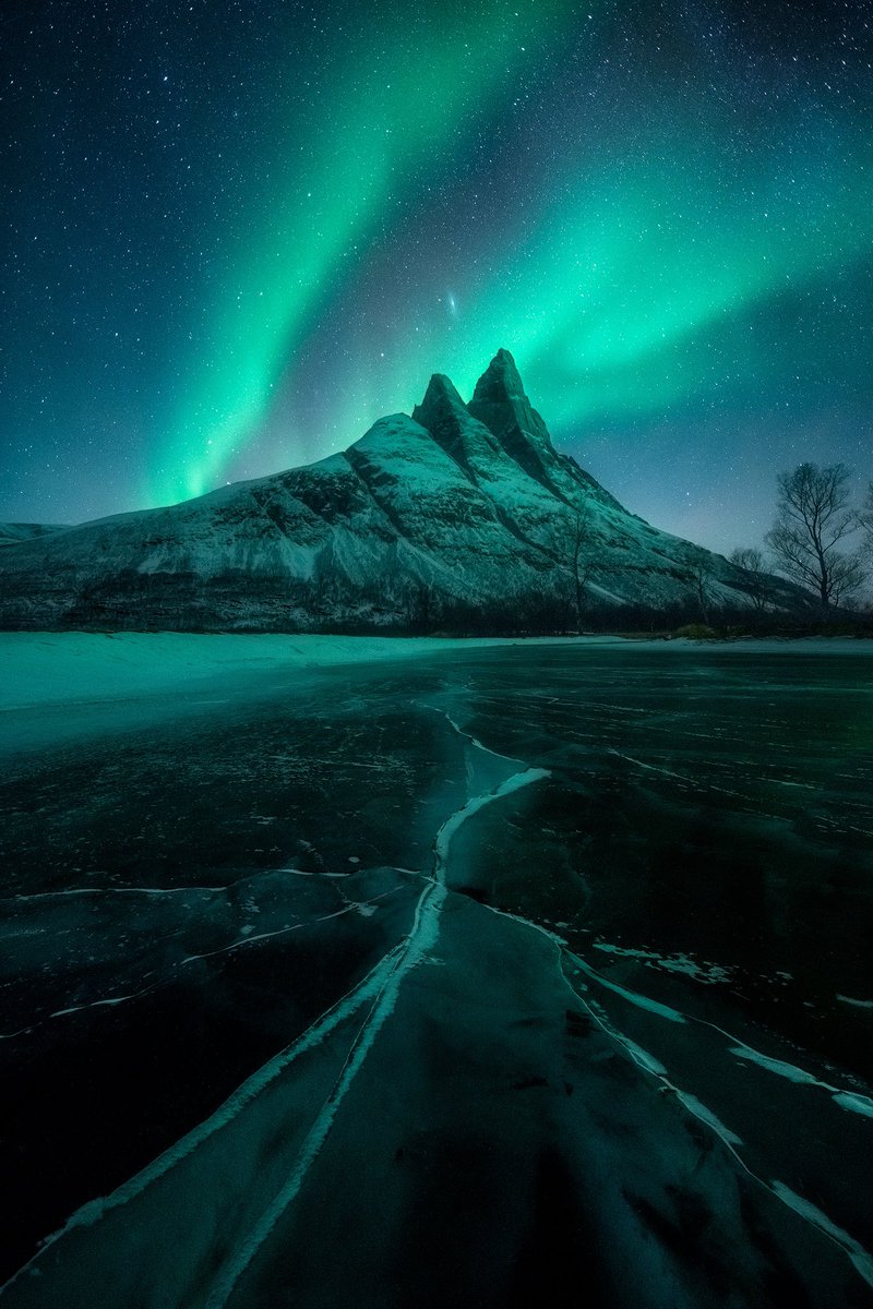 ryandyar's tweet image. The Norwegian peak, Otertinden, above a frozen river and under a night sky.