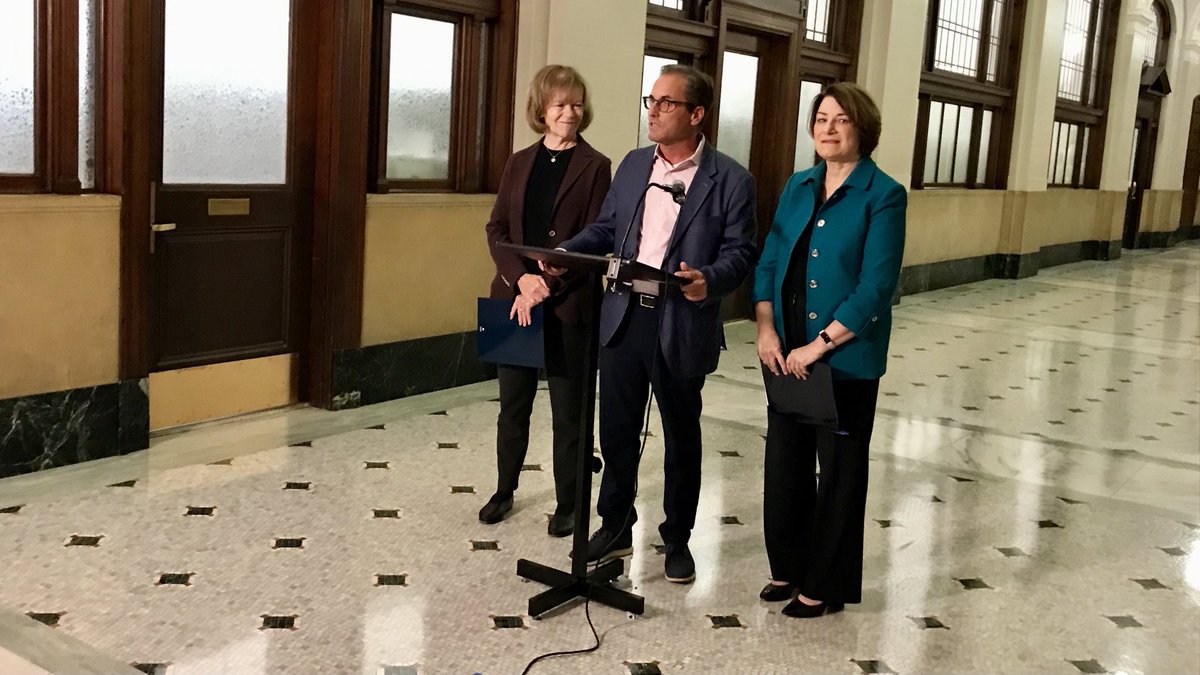 JohnCroman's tweet photo. David Wellstone appears with US Senators Tina Smith and Amy Klobuchar as they announce effort to rename Minneapolis Federal Building for the late Sen. Paul Wellstone, who died with 7 others in a plane crash 20 years ago today https://t.co/cBpZdfU4Bd