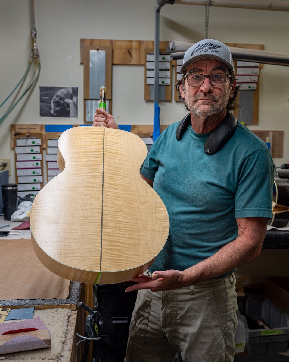 Longtime team member Ed tapes off ivoroid binding then sprays lacquer on this SJ's gorgeous maple back and sides before showing it off to the camera. #handmade #acousticguitar #luthiery #maple #atx #collingsguitars