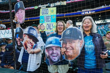 Fans holding signs with the faces of Cal Raleigh, J.P. Crawford, Eugenio Suárez and Scott Servais. 