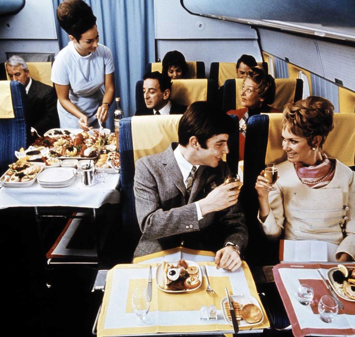 Havayolu şirketleri arasındaki rekabet 1960'lı yıllarda doruğa ulaşmıştı. Fotoğrafta bir Amerikan şirketine ait uçağın business class bölümünde yapılan yemek servisi görülüyor.