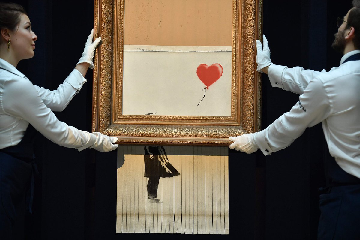 ohmyispy's tweet photo. the nxde mv is such a gold mine of references. here they're recreating that time banksy destroyed his picture at the auction, right after it got sold for $1.4M https://t.co/J1wnjnU4VD