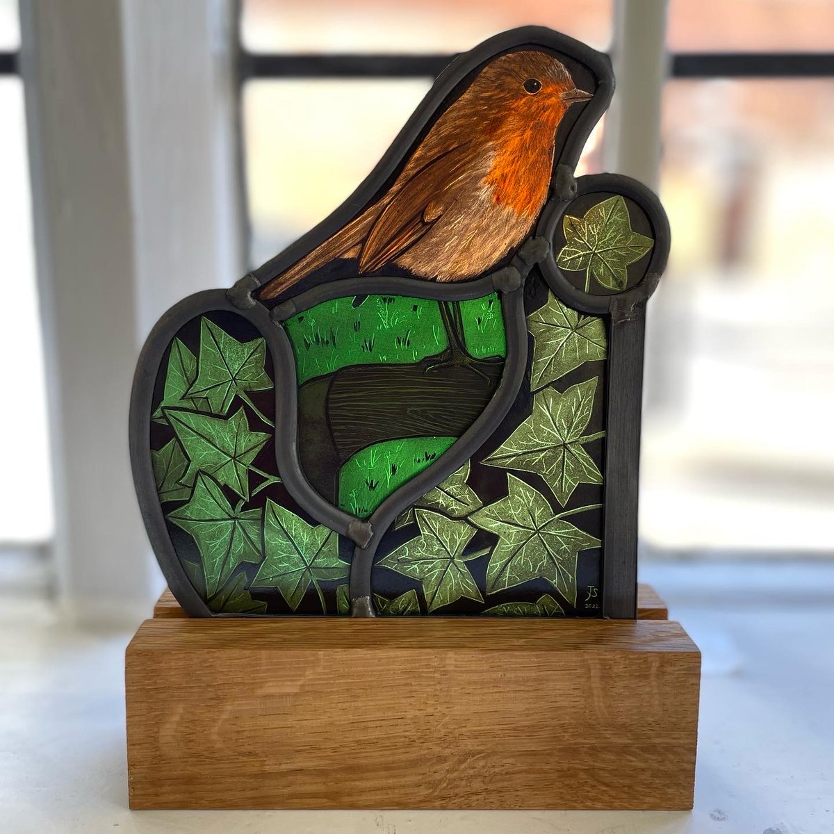 'Gardener's Friend' - painted and enamelled stained glass on an oak plinth.  Displayed here as part of my 'Two Hedges' exhibition at <a href="/newashgate/">New Ashgate Gallery</a> 

#stainedglass #stainedglassartist #glassart #gardenbirdsUK #robin #robins #ivy