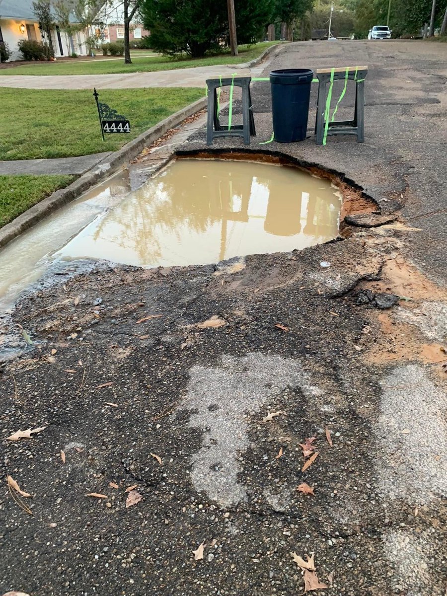 WLBT's tweet photo. A postal worker parked on Woodlark Street in NE Jackson Monday afternoon, according to a resident. Moments later, the ground gave way beneath him, after water had been running about 48  hours. Neighbors have now set up a makeshift roadblock to protect drivers. https://t.co/YVg4JNkZ19