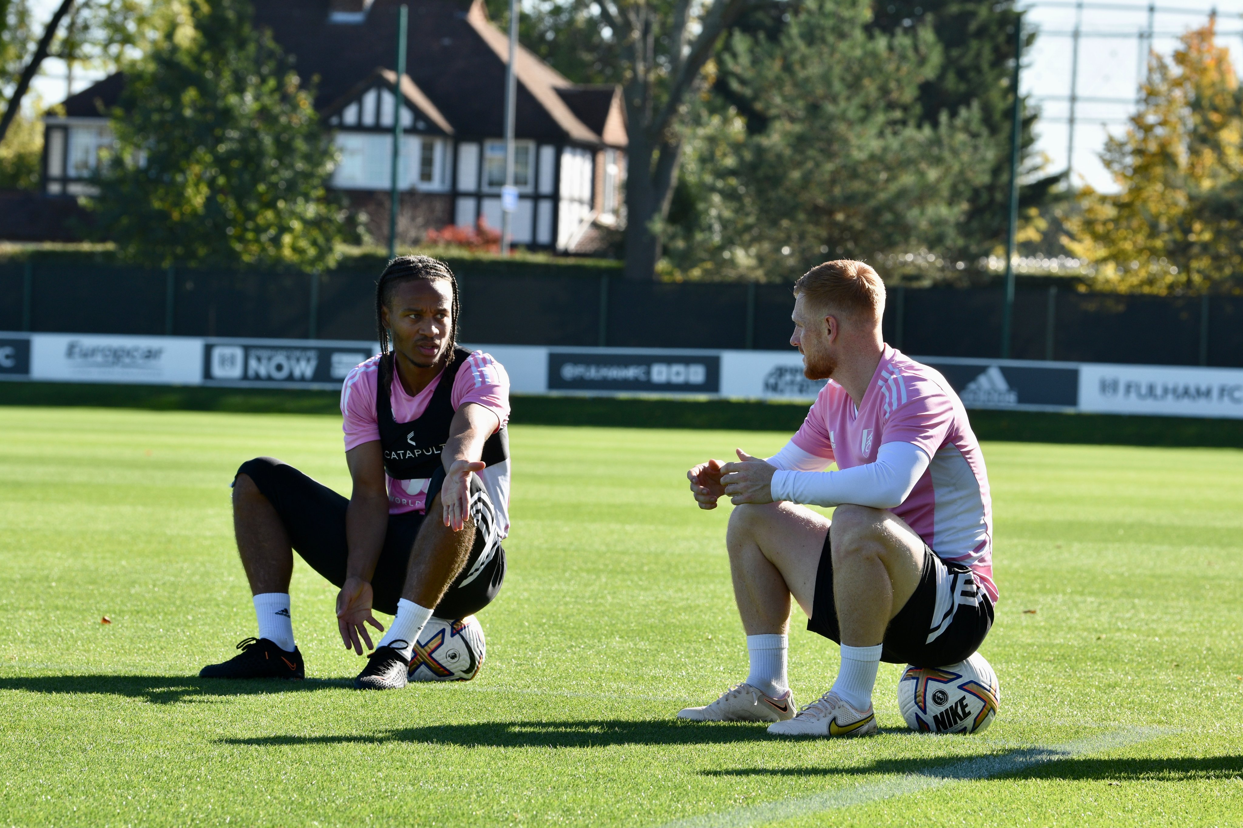 Bobby De Cordova-Reid and Harrison Reed sit on footballs after a training session at Motspur Park.