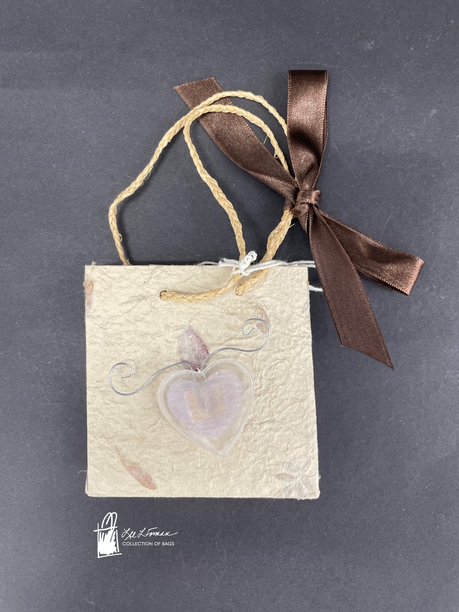 292/365: This miniature bag appears to be made from recycled or handmade paper. It bears the imperfect texture of the paper making process along with embedded flower petals, creating a 'softer' appearance to the material. 