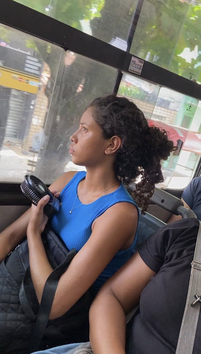 Simplesmente a mana icônica com seu ventilador portátil no ônibus LOTADO às 13:30h. ✨