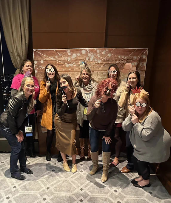 Nine educators posing with photo props.