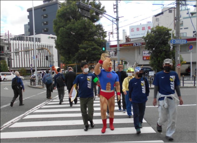 【東成警察署の取組】
東成警察署では、高齢者に向けて防犯教室を行った後、防犯正義超人キン肉マンと共にウォーキングパトロールを行いました。
署員とおそろいのＴシャツを着てまちを歩き、健康的に啓発活動を行い、パトロール終了後は、音楽隊の演奏とよしもと住みます芸人の漫才を見て頂きました。
