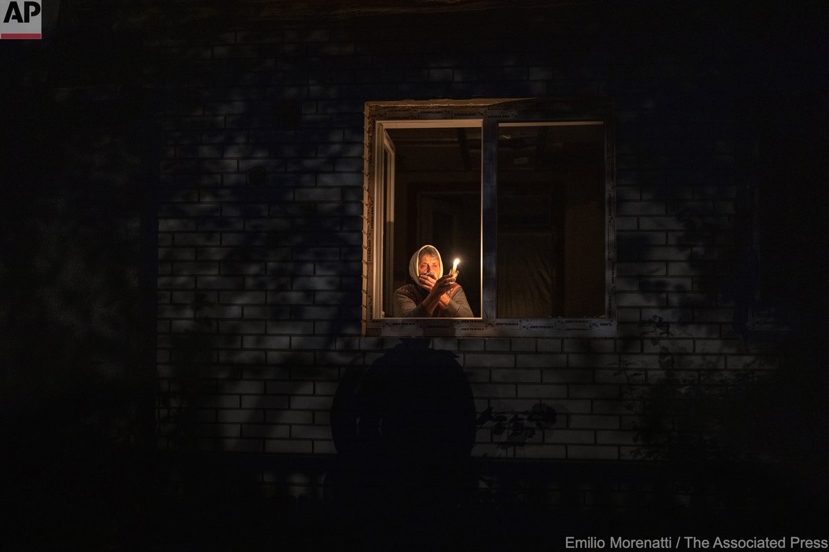 Catherine, 70, holds a candle inside her house during a power outage in Borodyanka, Ukraine, Oct. 20, 2022. Russian airstrikes cut power and water supplies to hundreds of thousands of Ukrainians.