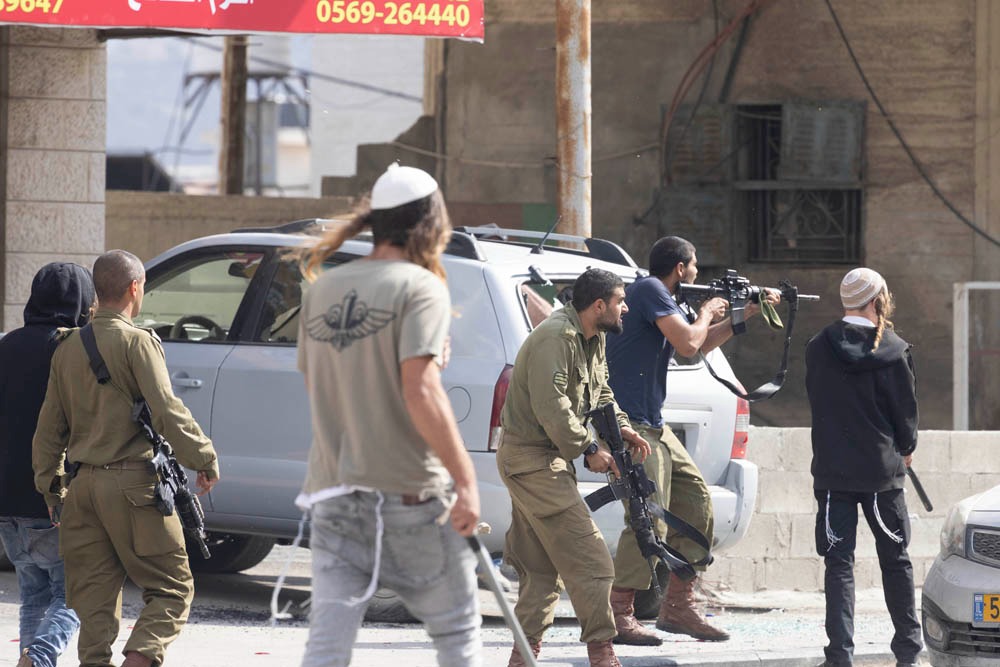 Israel's leaders are up in arms about an incident in which settlers attacked soldiers yesterday. One of the assailants is an off duty soldier. I think this October 13, 2022, photo by @OrenZiv_ shows the gap between soldiers and violent settlers has shrunk to non-existence.