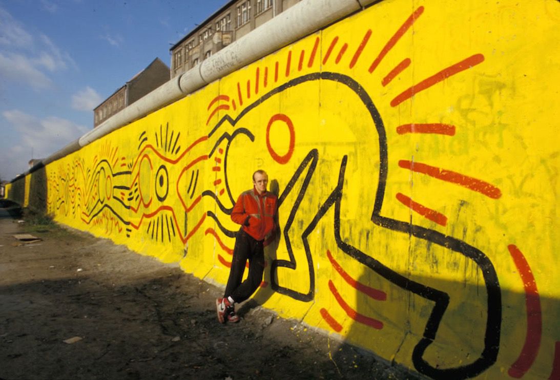 #ArtMoments Keith Haring | 'Berlin Wall Mural' In 1986, the artist painted a 300-meter long piece on the border between East and West Germany. The figures' interlocking hands symbolise the hope for unity.