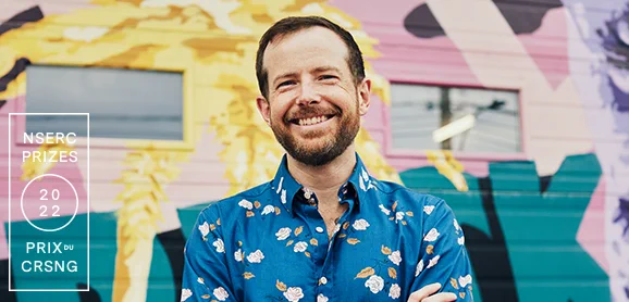 IMAGE: Portrait of Blake Richards (McGill University) in front of a mural, with a logo in white for NSERC PRIZES 2022, on the left.