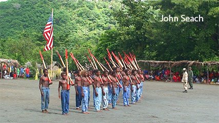 John Frum Movement in Tanna, Vanuatu. The movement is often known as a 'cargo cult' but is more accurately described as a Melanesian contact culture. Photo shows a military drill using imitation bamboo rifles in front of an American flag. #Vanuatu #johnfrum #cargocult