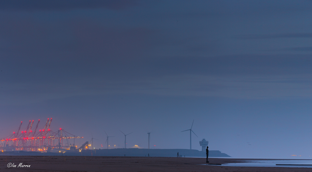 IanMurrenUK's tweet photo. Blue hour Mist amongst the @PeelPorts giraffes #anotherplace #ironmen #industry #dockyard @IronMenCrosby #photography #bluehour #turbines #navigationlights https://t.co/6OayaivM90