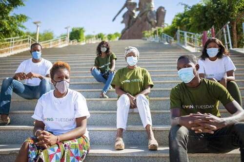 The GivingTuesday Senegal team wearing their GivingTuesday shirts and sitting on the steps while they plan a generosity takeover!