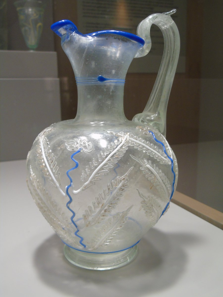 DrJEBall's tweet image. A beautiful little #Roman glass wine-jug, in clear glass with blue &amp;amp; white decorations. It was found buried in a Roman-period grave in Belgium, which explains the great condition it survives in #RomanArchaeology