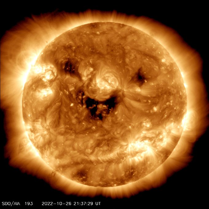 Satellite imagery from NASA's Solar Dynamics Observatory shows the Sun in ultraviolet light colorized in light brown. Dark patches on the Sun's surface are in the shape of a smile. 