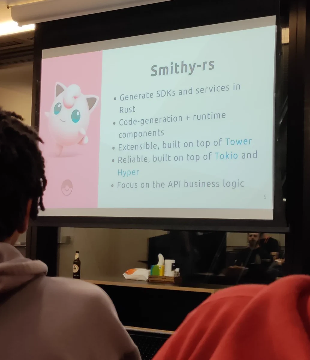 Photo of a slide
Left of slide is a picture of a Jigglypuff.
Right of slide is titled "smithy-rs" and the content (https://github.com/crisidev/smithy-rs-pokemon-service/blob/main/docs/slides.md#smithy-rs) is as follows:


 -  Generate SDKs and services in Rust
 -  Code-generation + runtime components
 -  Extensible, built on top of Tower
 -  Reliable, built on top of Tokio and Hyper
  - Focus on the API business logic