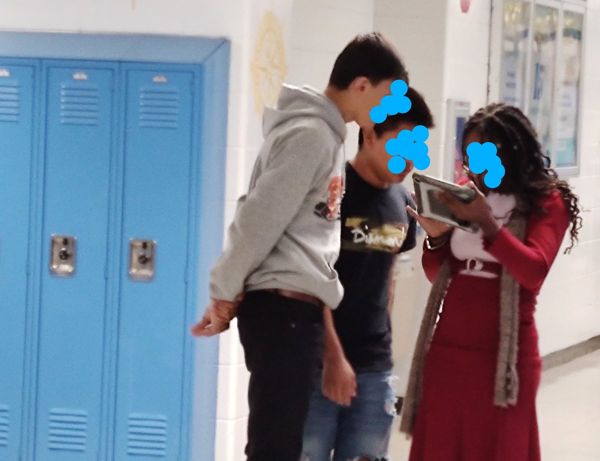 This is America. 3 students from different continents with their heads together working on a project.