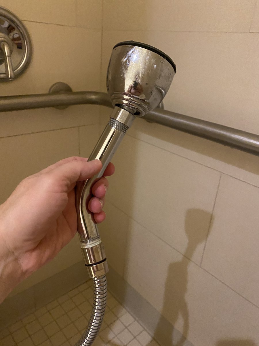 AccessNerds's tweet photo. Not all hand held shower units are created equal. This one was a fixed shower head that was stuck into a hose. Creative, but not very user friendly because you had to hold it at such a strange angle. #AccessNerds #ADA #shower #hotel #accessibility https://t.co/9oWJKR31qr