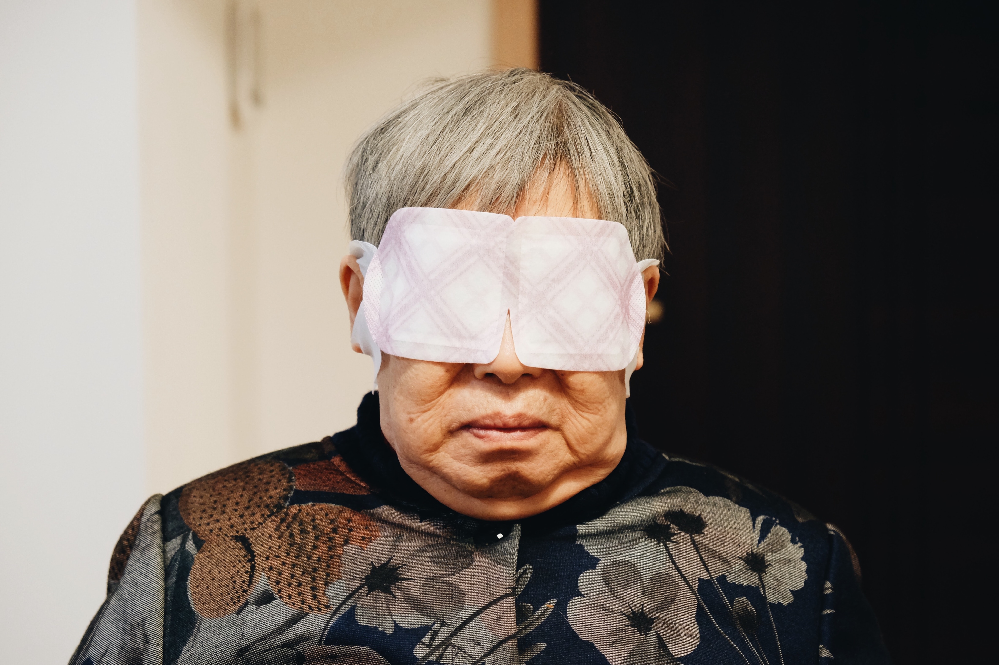 An old woman sleeping with a heat patch on the eyes