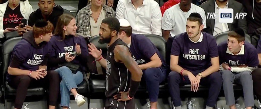 Fans wearing 'Fight Antisemitism' shirts sit courtside at Nets