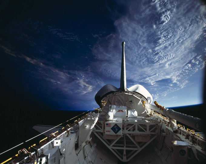 Photo taken November 1, 1992 by astronauts on STS-52 looking at the aft section of Space Shuttle Columbia. Behind the shuttle, Earth can be seen with the towering clouds of thunderstorms appearing on its deep blue surface.