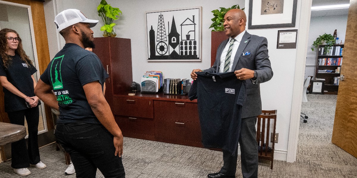 USCUpstate's tweet photo. Some of our talented Cybersecurity students stopped by Chancellor Harris' office to gift him one of their new "What is Your Digital Footprint" T-shirts, designed by Studio Upstate. We are so excited that soon we will graduate our first student from this tough program. Stay tuned! https://t.co/YhYtXnuEHV