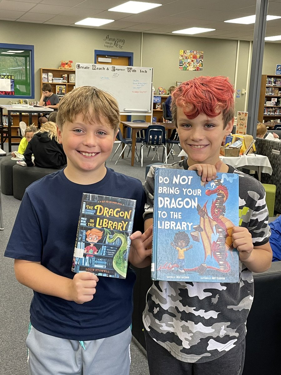 hmsbearapy's tweet photo. Good times in the library today! These boys found some fun #dragon books. Check out the titles. #440Proud #HMSPride #library #therapydog https://t.co/Z3GVhP7PBt