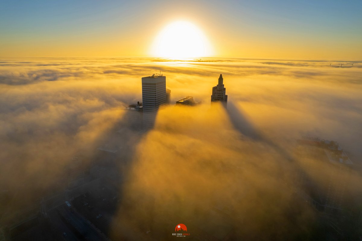 MikeCohea's tweet image. The rising sun casts long shadows of the Providence, #RhodeIsland skyline on the thick fog blanketing the area this morning.