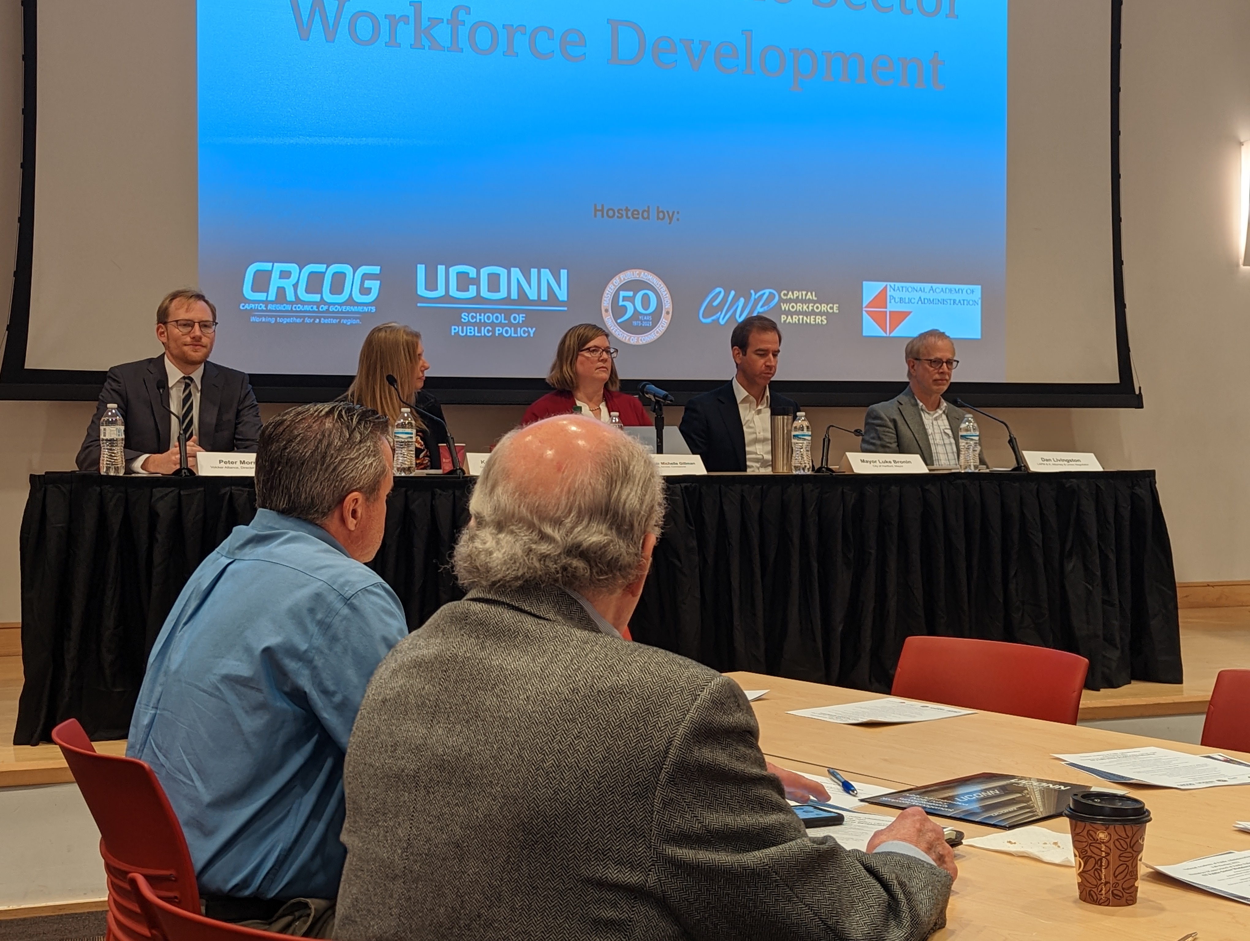 Photo of panelists in front an audience and a slide that reads "Connecticut Public Sector Workforce Development"