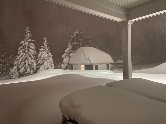 A suburban backyard at night completely blanketed in five feet of fluffy snow, covering the trees and a shed in thick white caps